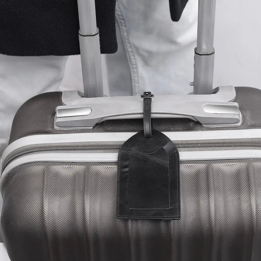 Black suitcase with a luggage tag attached, blurred background